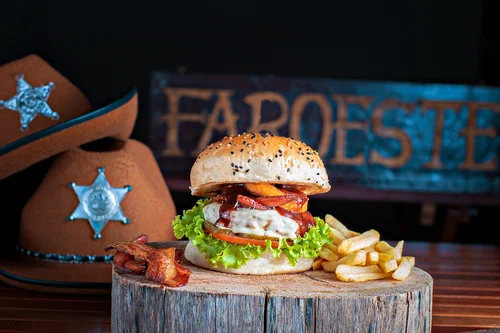 Hambúrguer artesanal Faroeste com blend bovino 150g na brasa, bacon crocante e batata frita rústica